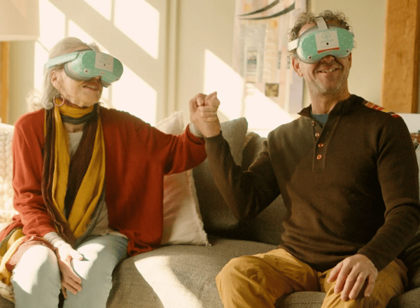 Stylish senior woman and her son wearing Rendever headsets holding hands